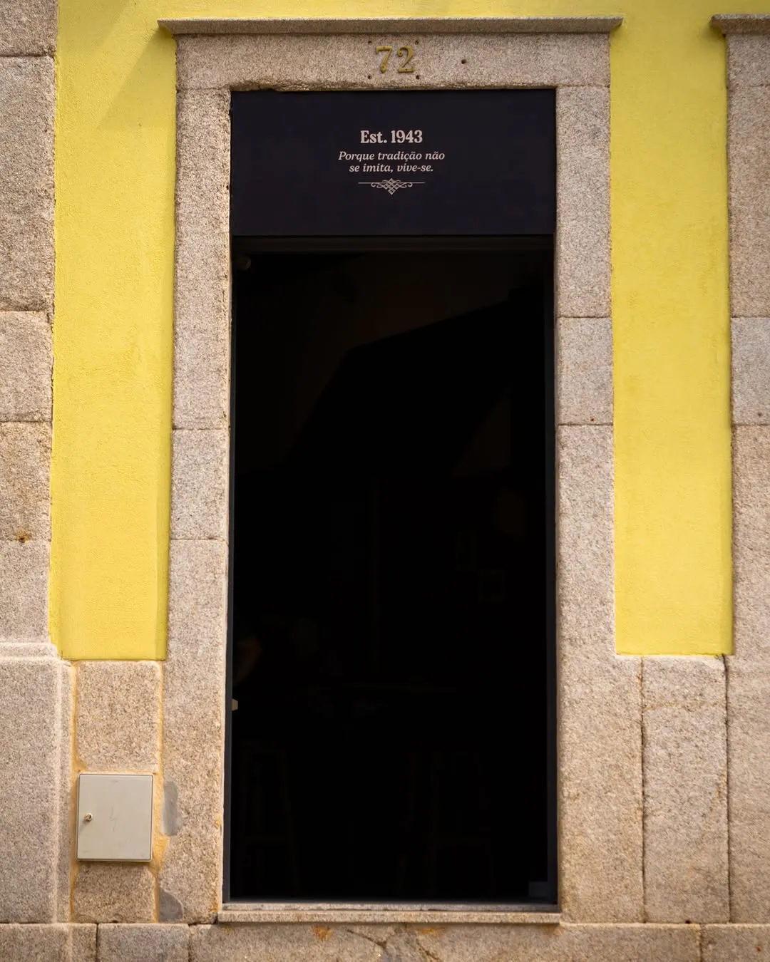 A porta amarela do número 72, com Est. 1943 no lintel